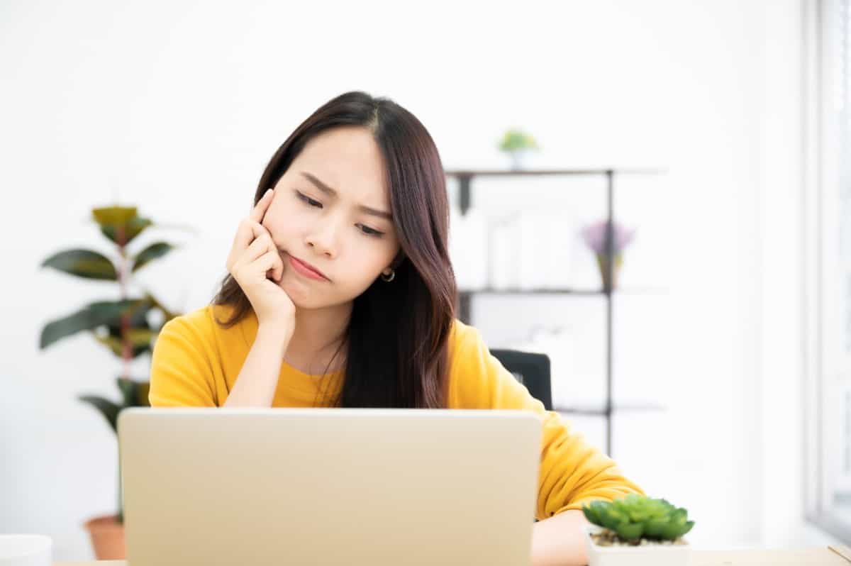 Young woman thinking in front of the laptop.